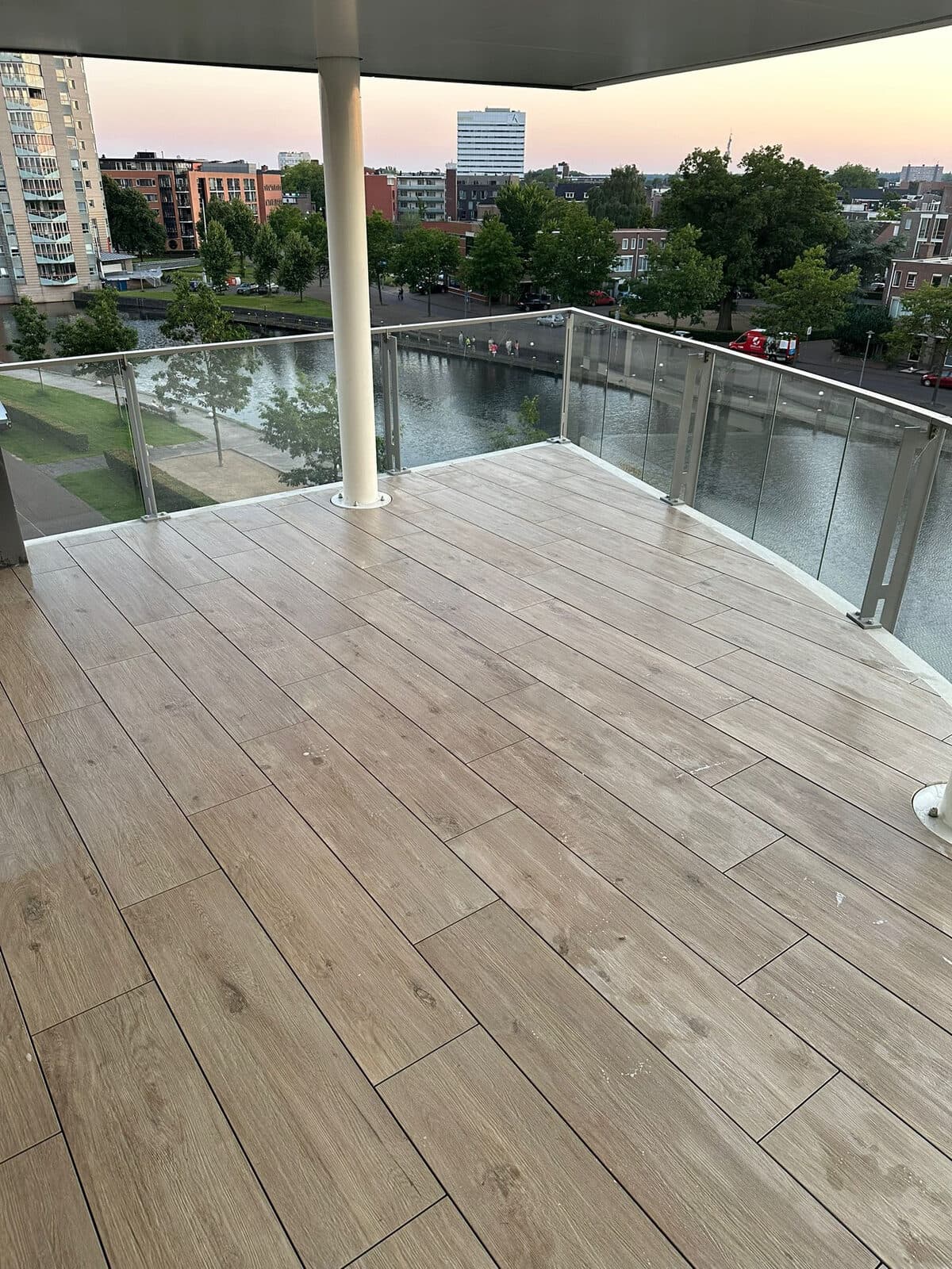 Ruim balkon met lange houtlook tegels en bij zonsondergang uitzicht over het water