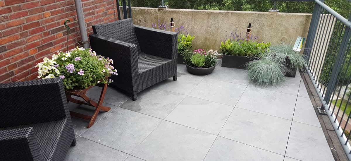 Balkon met grijze 2 cm tegels op tegeldragers, met stoelen en planten