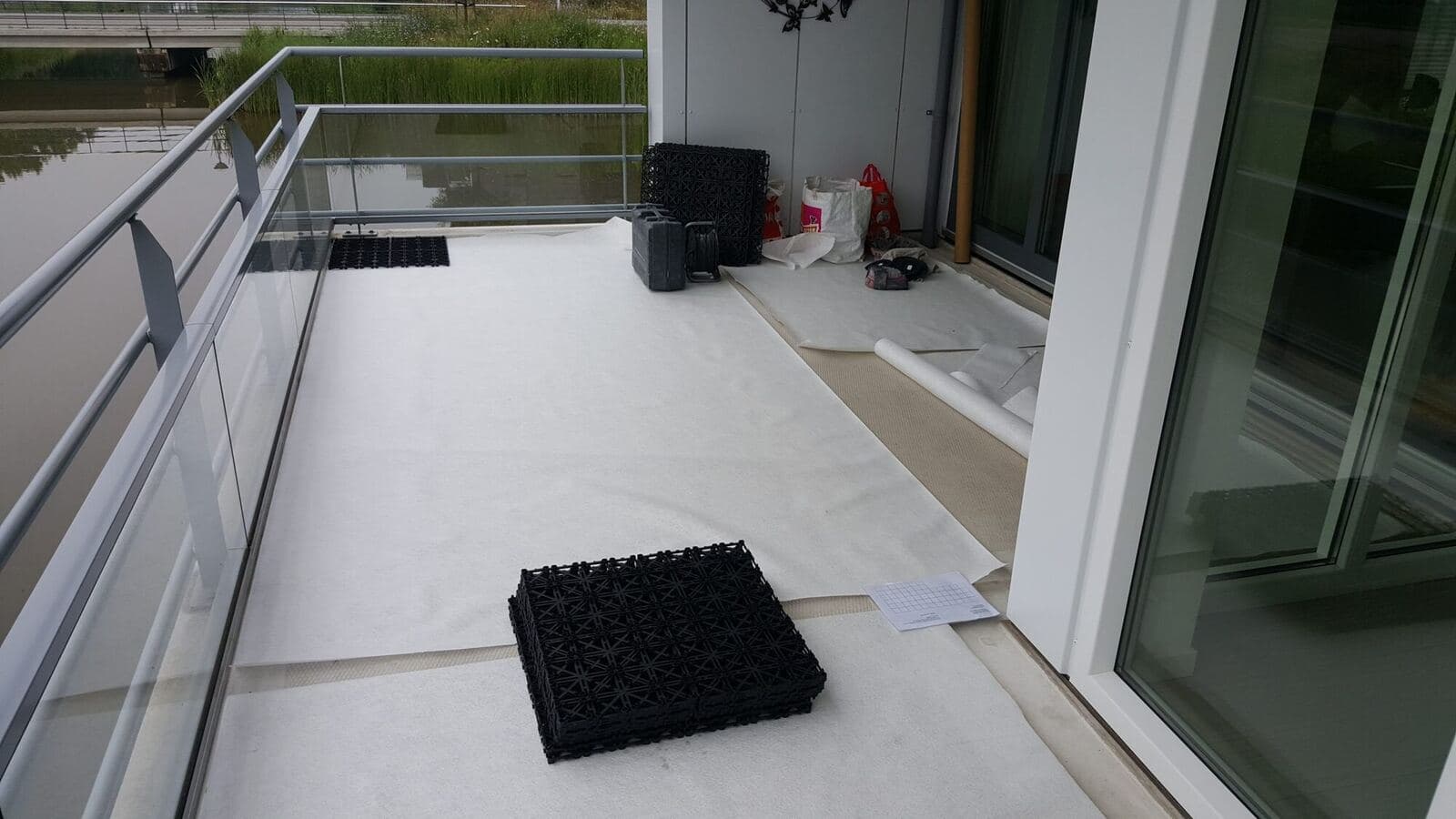 Balkon in voorbereiding: worteldoek over de dakbedekking en zwarte ITS draagmatten klaar om te klikken