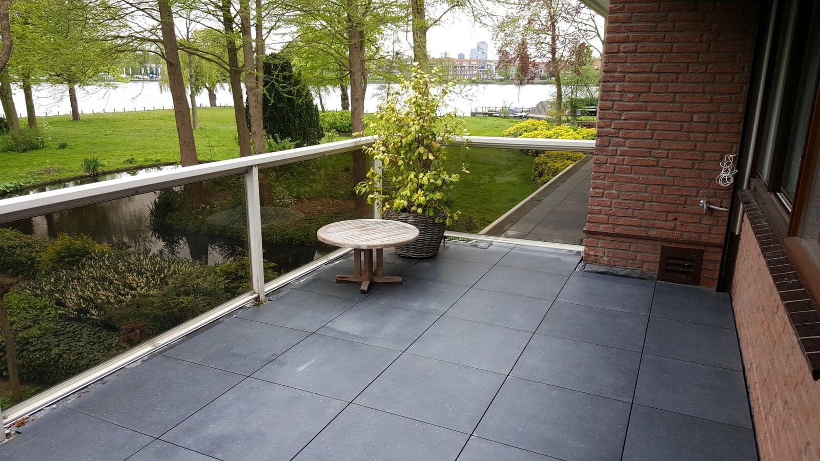 2 cm tegels dakterras Rotterdam: Dakterras met donkere hardsteenlook tegels, uitkijkend over het water