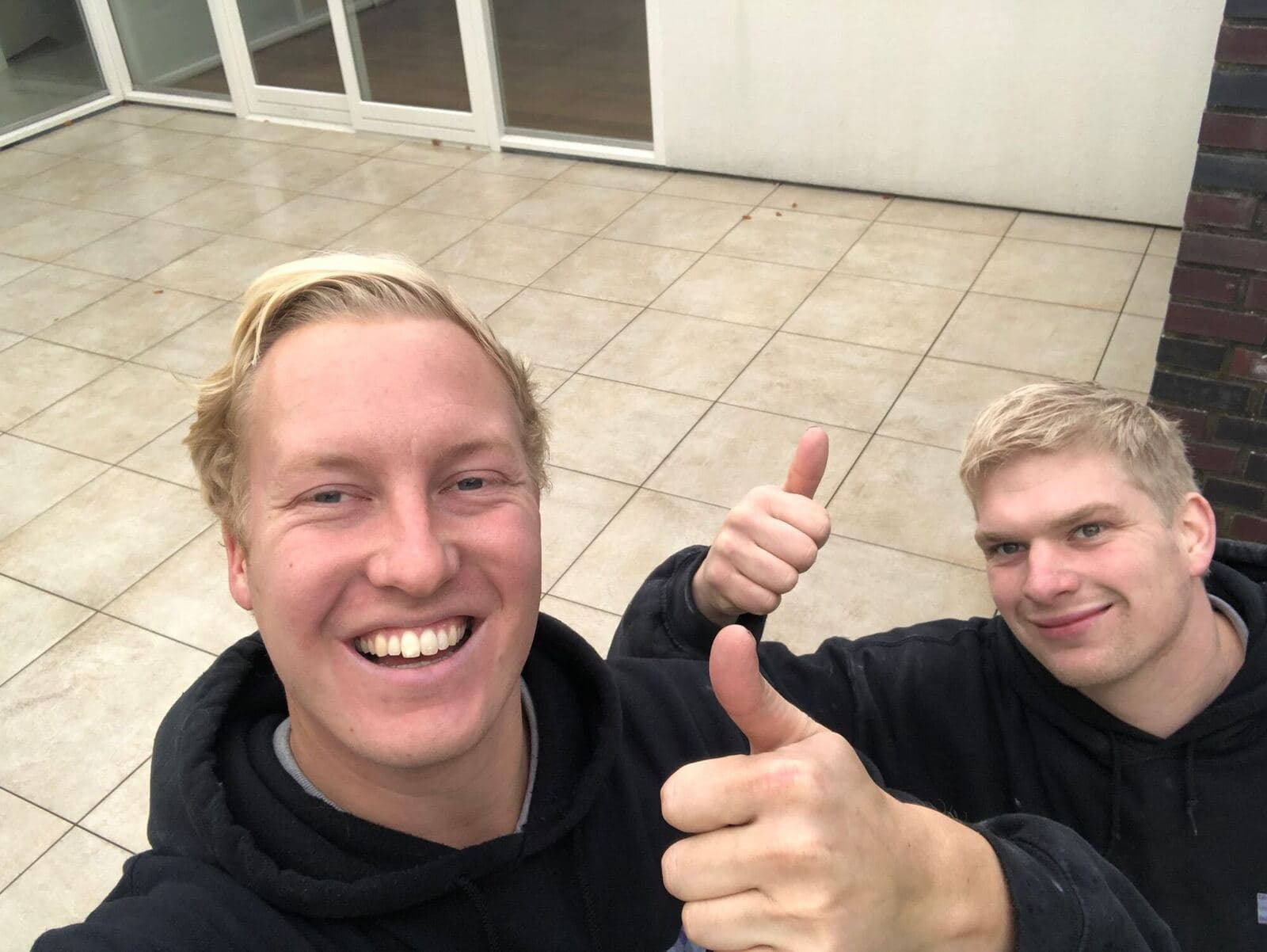 Twee tegelzetters met de duim omhoog op een pas betegeld terras
